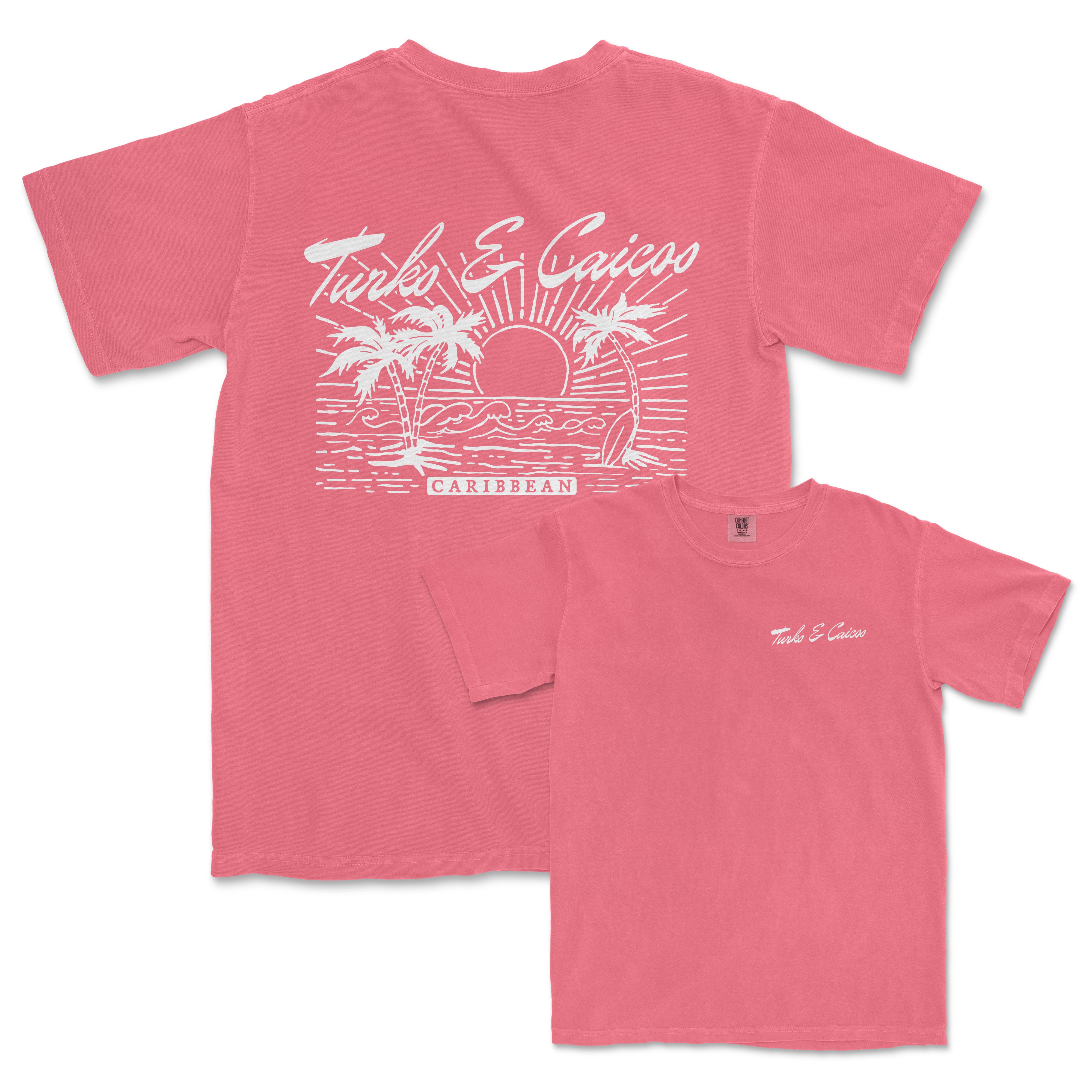 a pink t - shirt with a picture of a sunset and palm trees